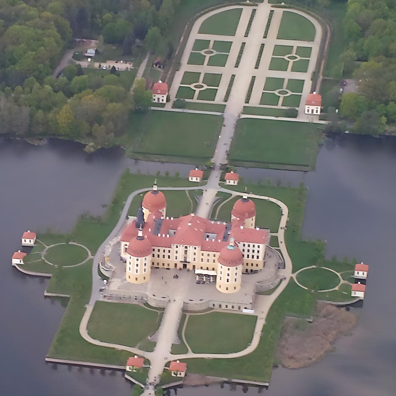 Majestätisches Barockschloss mit vier Türmen und mit prachtvollen Gartenanlagen, umgeben von Wasser – eindrucksvoll aus der Luft fotografiert.